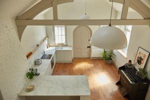 a large kitchen with white counters and a piano at Converted Chapel with Scandi design interior in New Buckenham