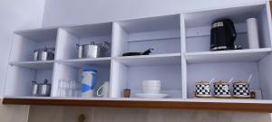 un estante blanco con platos y utensilios. en Pretty stay en Nairobi
