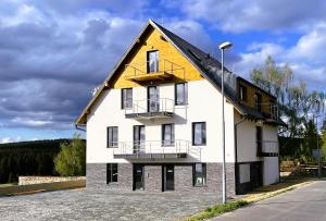 uma casa branca com um telhado amarelo numa rua em Apartmán Plešivec u sjezdovky em Abertamy