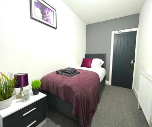 a bedroom with a bed with a purple blanket at Chantry Suites in Grimsby