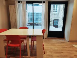 uma sala de jantar com uma mesa e cadeiras vermelhas em La petite maison em Dinan