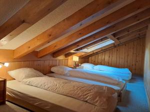 three beds in a room with wooden walls at Apartment Pinot Gris combles by Interhome in Verbier