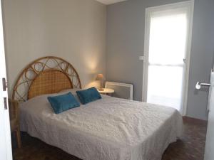 a bedroom with a bed with two blue pillows on it at Apartment Maisons sur la Plage by Interhome in Gruissan