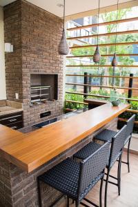 uma cozinha com um grande bar de madeira com 2 cadeiras em Apartamento em São Paulo, Vila Madalena em São Paulo