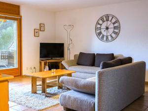 a living room with a couch and a clock on the wall at Apartment Caroubier 2 by Interhome in Ovronnaz