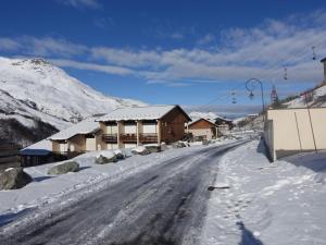 una calle cubierta de nieve con casas y un remonte en Apartment Les Asters-30 by Interhome, en Les Menuires