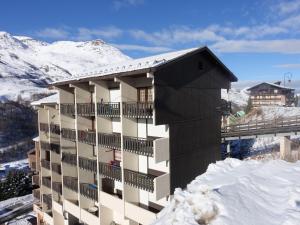 a building in the snow with mountains in the background at Apartment L'Argousier-1 by Interhome in Les Menuires