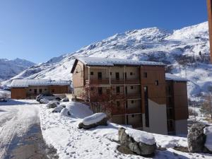 a building in the snow in front of a mountain at Apartment Les Asters-27 by Interhome in Les Menuires