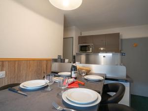 eine Küche mit einem Tisch mit Tellern und einer Flasche Wein in der Unterkunft Apartment Le Jettay-15 by Interhome in Les Menuires