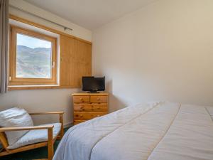 Schlafzimmer mit einem Bett, einem TV und einem Fenster in der Unterkunft Apartment Le Jettay-15 by Interhome in Les Menuires