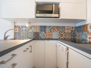 una cucina con armadietti bianchi e forno a microonde di Apartment Armoise-1 by Interhome a Les Menuires