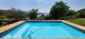 - une piscine bleue avec vue sur l'eau dans l'établissement Da Gama Lake Cottages - Coral Tree and Cormorant Cottages, à White River