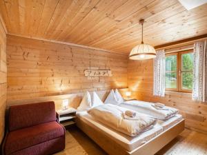 a bedroom with a bed and a chair in a room at Chalet Gnadenalm - OBR103 by Interhome in Obertauern