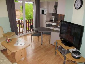 a living room with a flat screen tv and a kitchen at Apartment An der Eine-1 by Interhome in Stangerode