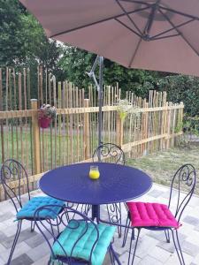 a purple table with four chairs and an umbrella at Le gîte des cascades in Bassy