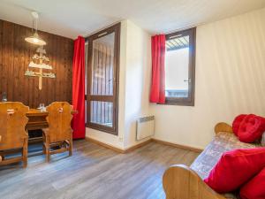a living room with a dining room table and red curtains at Apartment Armoise 73 by Interhome in Les Menuires