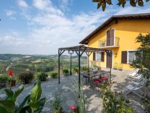 eine Terrasse mit einem Tisch und Stühlen sowie ein gelbes Haus in der Unterkunft Apartment San Michele-1 by Interhome in Vinchio