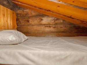 a bed with a white pillow and a wooden wall at Holiday Home Saarenkainalo by Interhome in Ruka