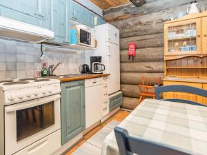 eine Küche mit blauen Schränken, einem Tisch und einem Herd in der Unterkunft Holiday Home Pajalan honka by Interhome in Kuusamo + 12 Fotos