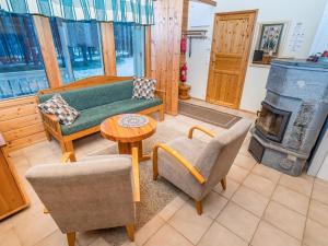 sala de estar con sofá, sillas y estufa de leña en Holiday Home Villa kuukkeli by Interhome, en Kuusamo