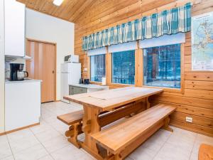a kitchen with a wooden table and two benches at Holiday Home Villa hilla by Interhome in Kuusamo +14 photos