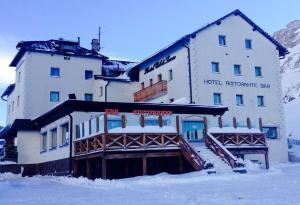 a snow covered ski slope with a building at Hotel Col di Lana in Canazei