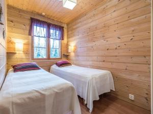 two beds in a room with wooden walls at Holiday Home Ylläs outa 1 by Interhome in Ylläsjärvi