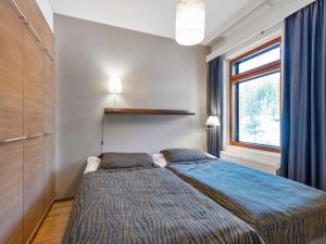 ein Schlafzimmer mit einem Bett mit blauer Decke und einem Fenster in der Unterkunft Holiday Home Ylläs chalets 2405 by Interhome in Ylläs