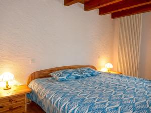 ein Schlafzimmer mit einem Bett mit blauer Bettwäsche und zwei Lampen in der Unterkunft Holiday Home Mona by Interhome in Leontica