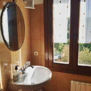 baño con lavabo, espejo y ventana en Casa Miret, en Vallvert de Queralt