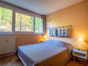 1 Schlafzimmer mit einem blauen Bett und 2 Fenstern in der Unterkunft Apartment Les Lauzes-4 by Interhome in Les Menuires