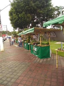 a farmers market with people standing under a canopy at Recanto Cheio de Cheiro in Guararema