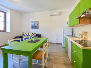 eine Küche mit grünen Schränken sowie einem Tisch und Stühlen in der Unterkunft Apartment Val-1 by Interhome in Sveti Juraj