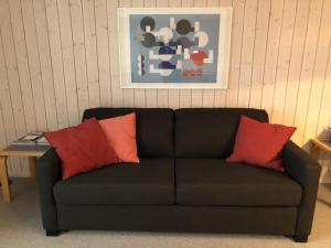 czarna kanapa z 2 czerwonymi poduszkami w pokoju w obiekcie Apartment Monique Nr- 1 by Interhome w mieście Gstaad