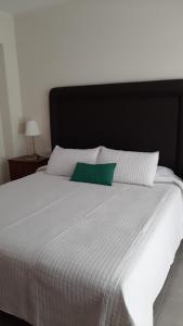 Una cama blanca grande con una almohada verde. en El Electron Parking Gratuito, en Santa Cruz de la Palma
