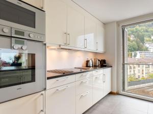 a kitchen with white cabinets and a large window at Apartment Le Belvédère D3-8 by Interhome in Montreux