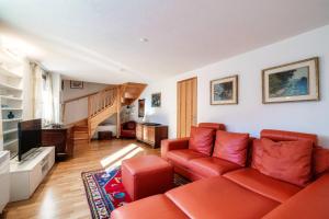 a living room with a red couch and a staircase at Chalet Nucleo 12 by Quokka 360 - Alpine Base for Bouldering Adventures in Leventina in Chironico