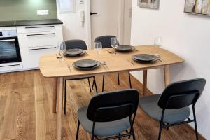 a wooden table with four chairs and wine glasses at Appartment Wolf Huber im Zentrum der Altstadt. in Feldkirch