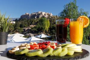 a plate of fruit on a table with a drink at Hotel Thissio in Athens