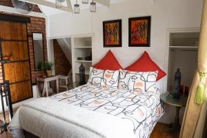 um quarto com uma cama grande e almofadas vermelhas em Honeysuckle Clarens em Clarens