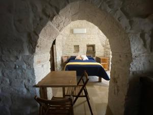 een slaapkamer met een bed en een tafel in een stenen muur bij Trullo Incanto in Ostuni