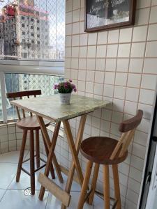une table avec deux chaises et une table avec des fleurs. dans l'établissement Apto com Piscina e Churrasqueira, à Praia Grande