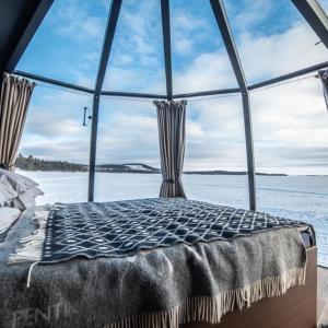 a bed in a room with a large window at Aurora River Camp Glass igloos & cabins in Kiruna