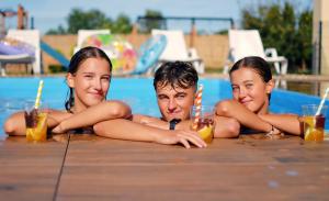 three people laying in a swimming pool with drinks at Amberia in Grzybowo +102 photos