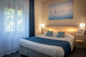 a bedroom with a bed and a window with sailboats at Logis REX HOTEL Lorient in Lorient