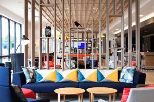a lobby with a blue couch and tables at Holiday Inn Express & Suites - Basel - Allschwil, an IHG Hotel in Basel