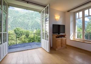 een kamer met een deur naar een balkon met een televisie bij La Grande Savoyarde in Chamonix-Mont-Blanc