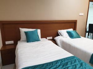 two beds with blue pillows in a hotel room at Kanmani Elite- A Perfect Home in Tiruchirappalli