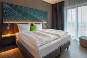 a bedroom with a large bed and a large window at elaya hotel kevelaer in Kevelaer