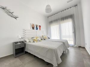 ein weißes Schlafzimmer mit einem Bett und einem Fenster in der Unterkunft Capistrano Garden in Nerja
